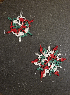 Crocheted Christmas snowflakes in red, green and white on a dark surface, blocked